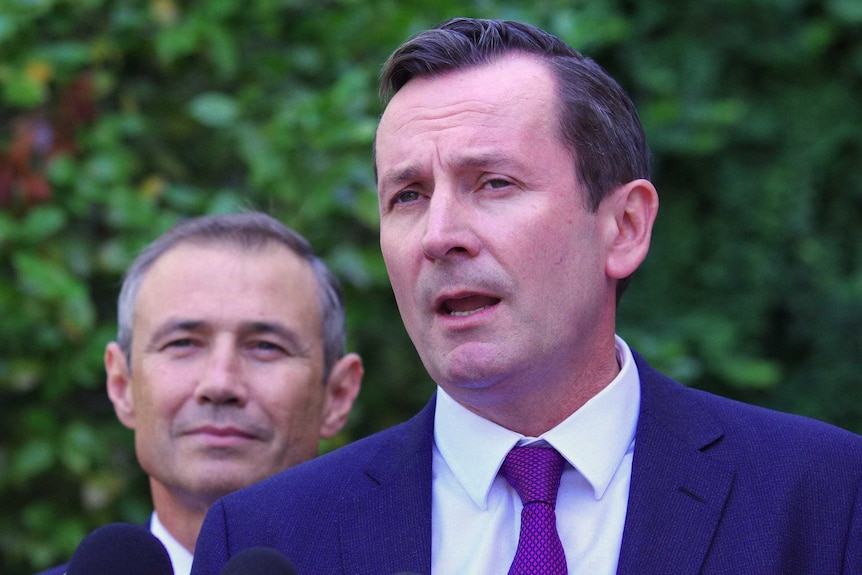 Headshot of Mark McGowan with Roger Cook behind him.