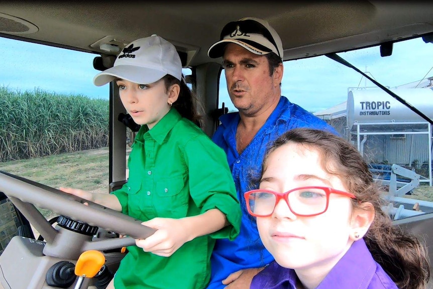 Frank Mugica and his daughters sitting in the cab of a tractor.