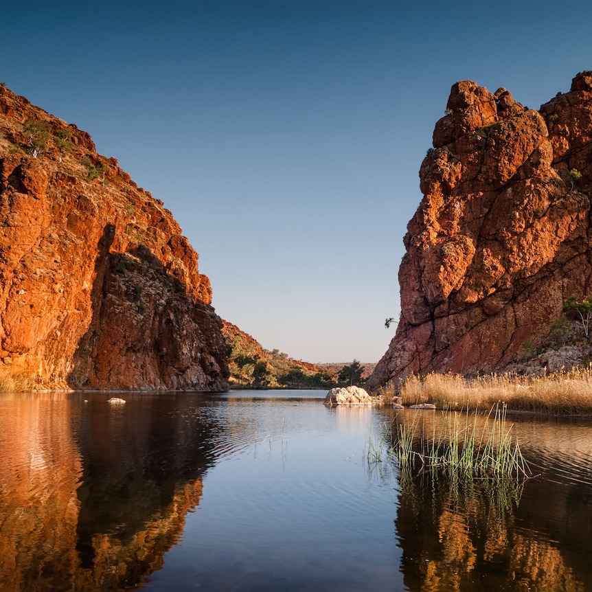 High red rocks surrounding a serene water hole.