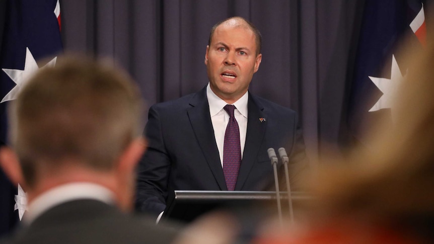 Mr Frydenberg is mid-sentence, and is slightly obscured by journalists sitting in the room.