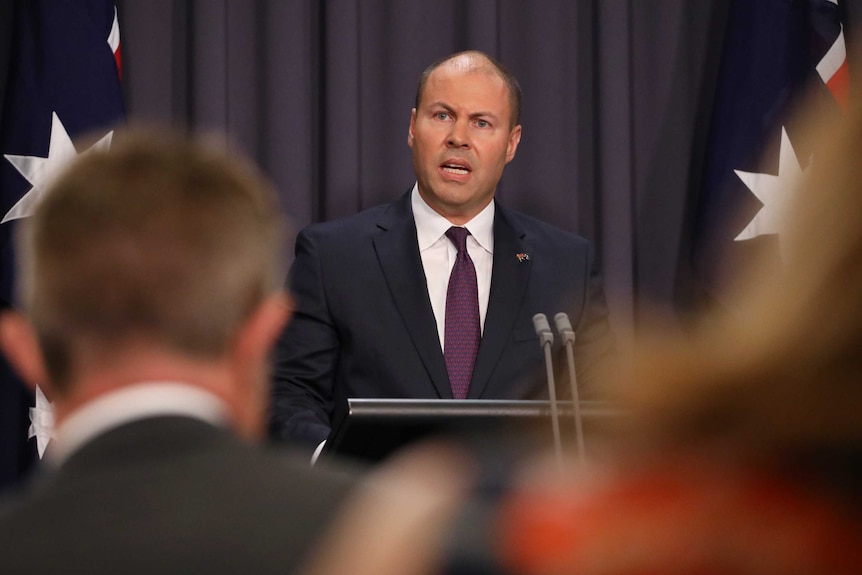 Mr Frydenberg is mid-sentence, and is slightly obscured by journalists sitting in the room.