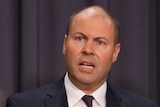 Mr Frydenberg is mid-sentence, and is slightly obscured by journalists sitting in the room.