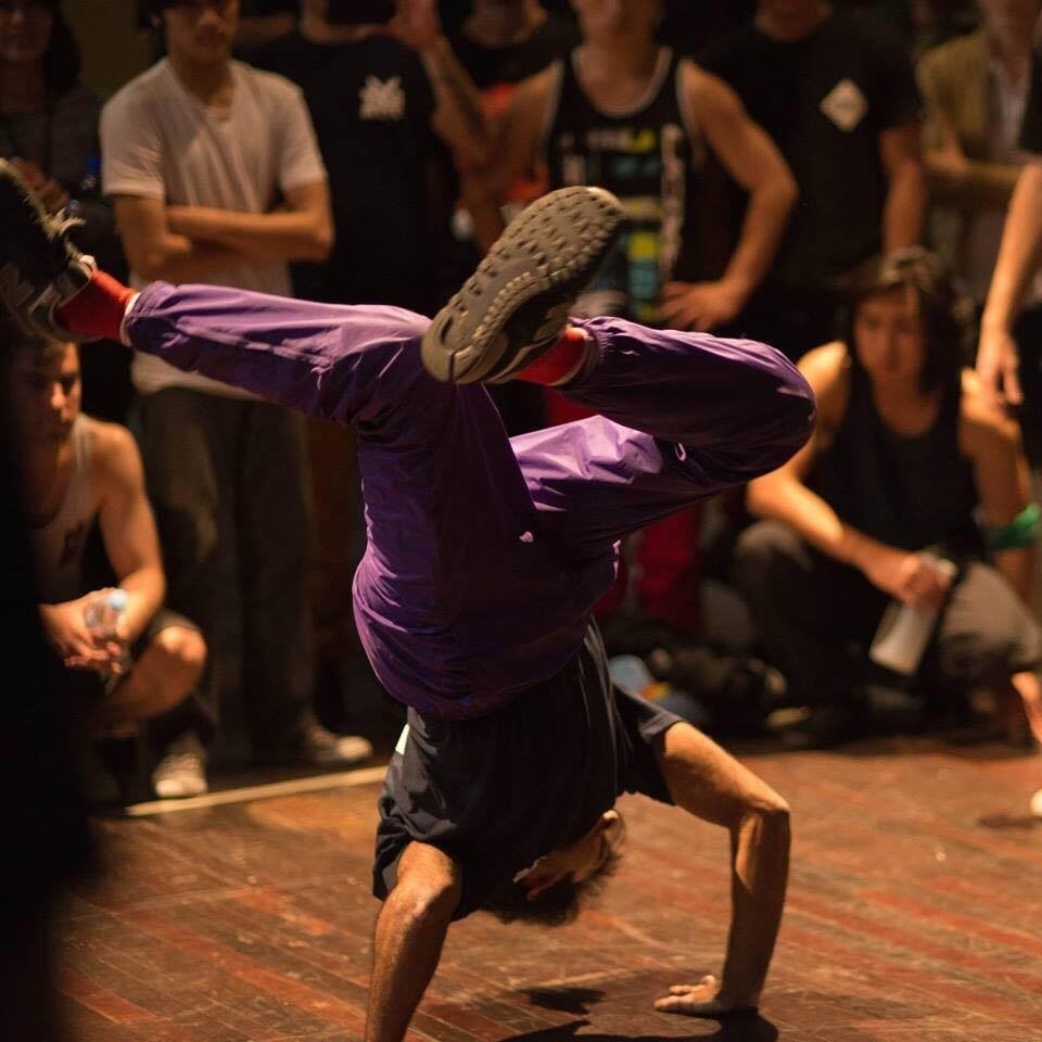 A man in purple pants doing a handstand.