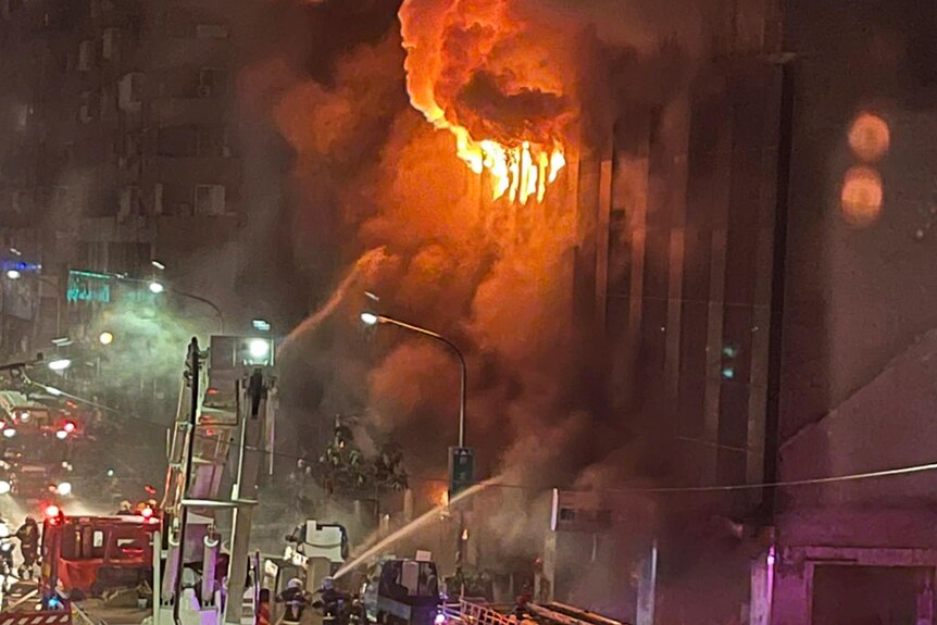 Flames and smoke billow out of an apartment building in southern Taiwan as emergency vehicles gather on the street