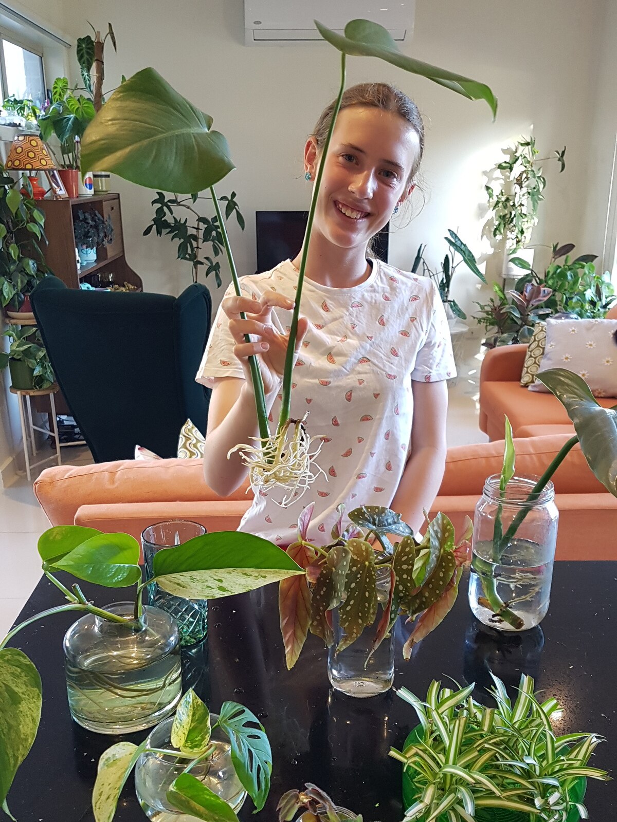 A young girl smiles while holding a plant cutting.
