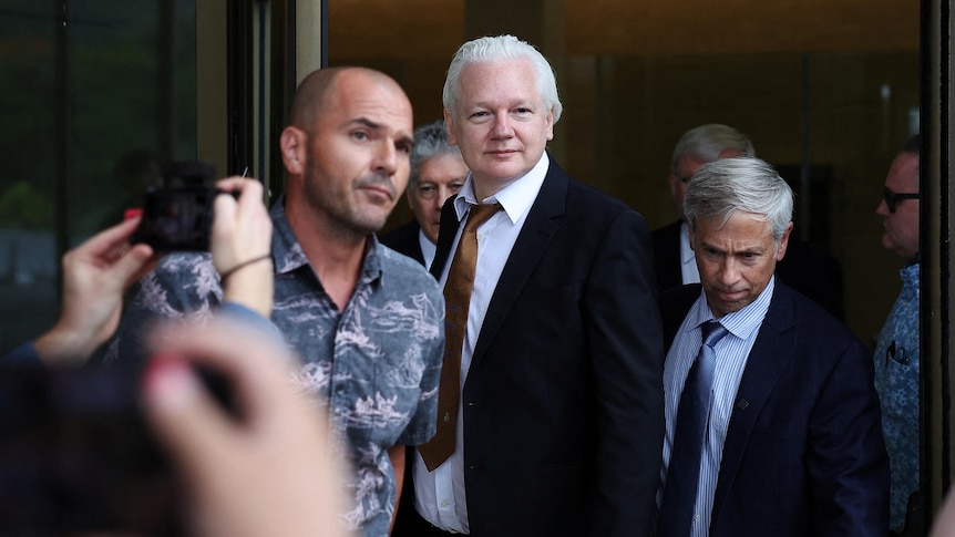 Julian Assange walks away free. Smiling.