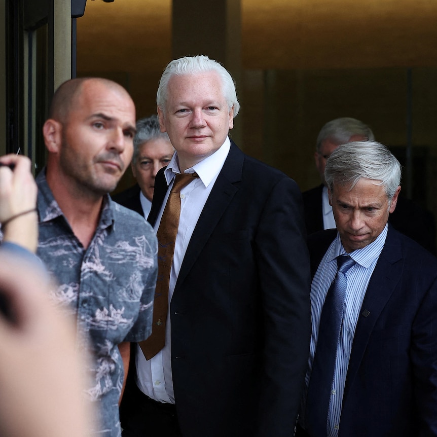 Julian Assange walks away free. Smiling.