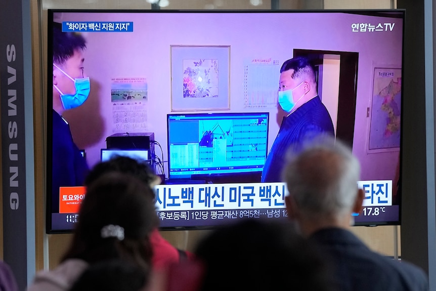 Oameni care se uită la un ecran TV care îl arată pe liderul nord-coreean Kim Jong Un
