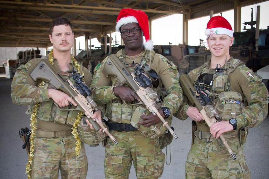 Australian Army soldiers holding guns and dressed for Christmas in Kabul, Afghanistan.