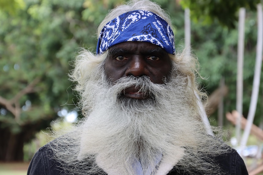 A portrait of a man with a blue head scarf and white beard.