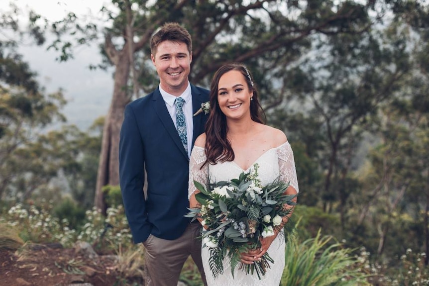 Courtenay Noakes in her wedding dress smiles at camera with her groom at Binna Burra.