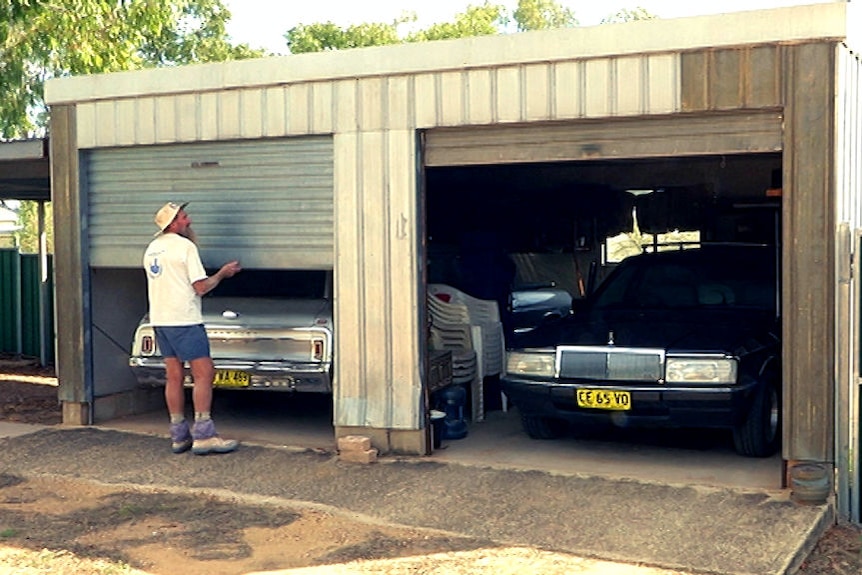 Man lifts roller door of shed