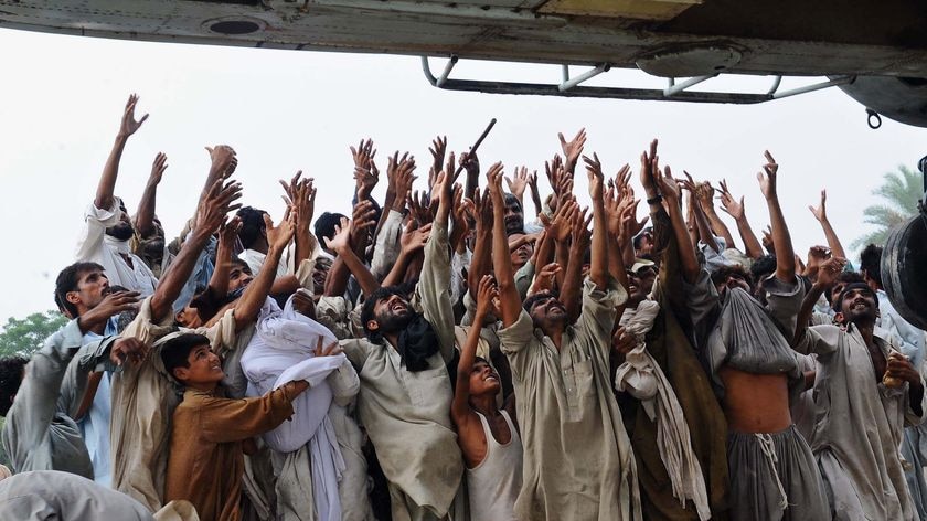 Pakistani flood survivors try to catch food bags being dropped from an army helicopter