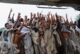 Pakistani flood survivors try to catch food bags being dropped from an army helicopter