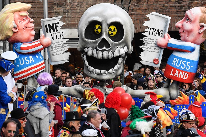 A float depicts cartoonish characters of Trump and Putin holding tattered treaty with big skull in the middle, nuclear symbols