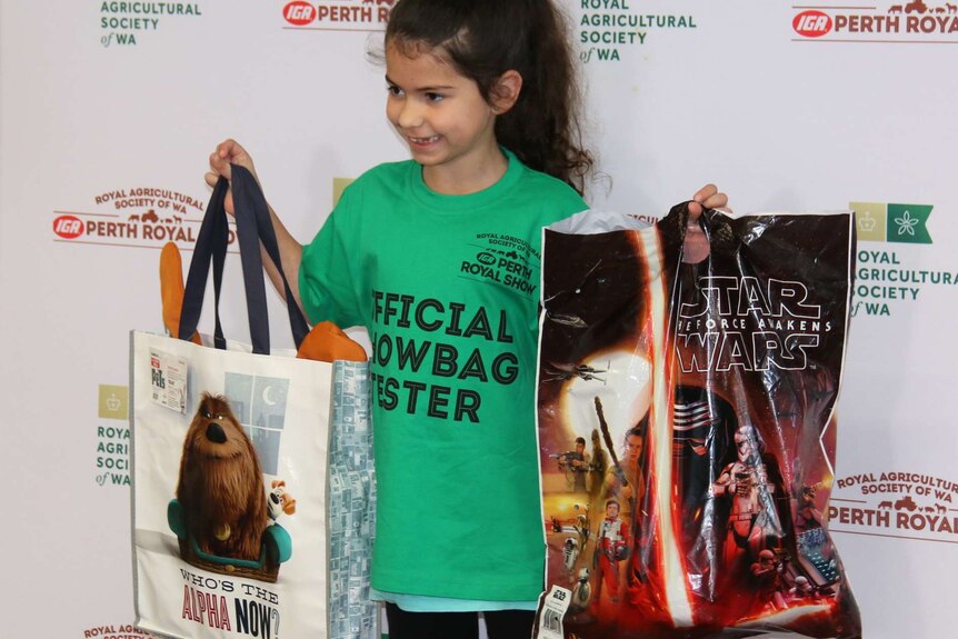 A girl holds up show bags for Star Wars and the Secret Life of Pets.