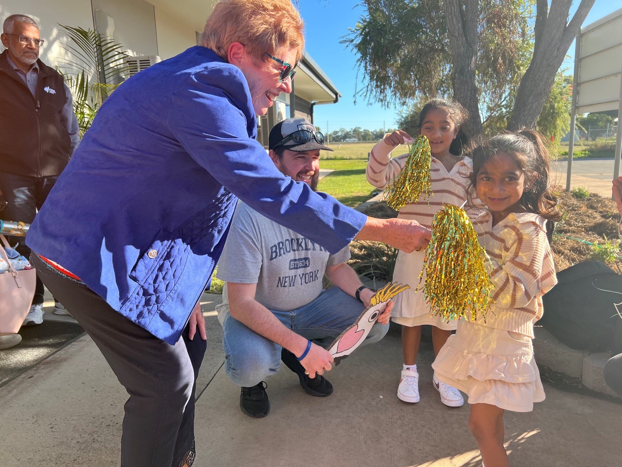 Two little girls are handed sparkly streamers at an airport.