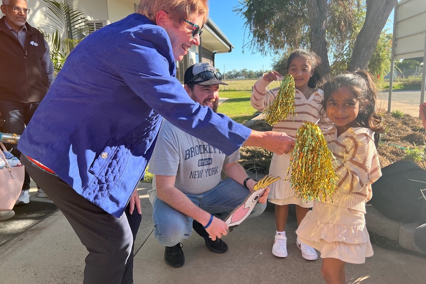 Two little girls are handed sparkly streamers at an airport.