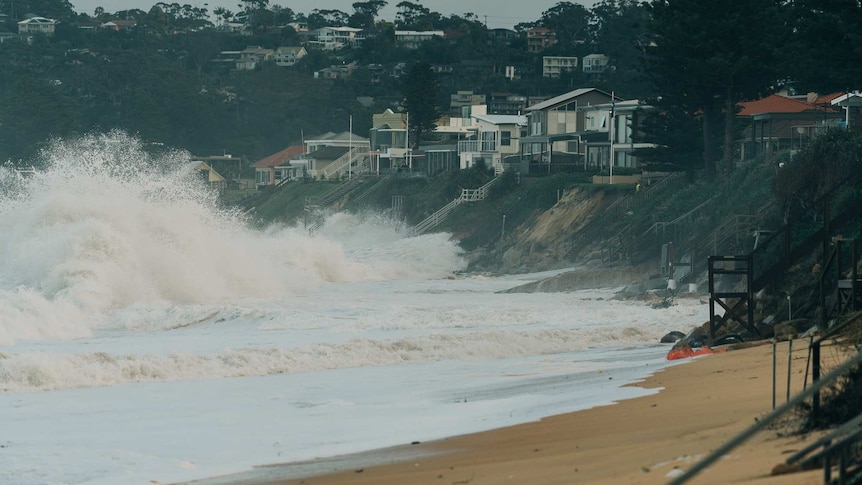 Waves break near homes causing cliffs to form from erosion