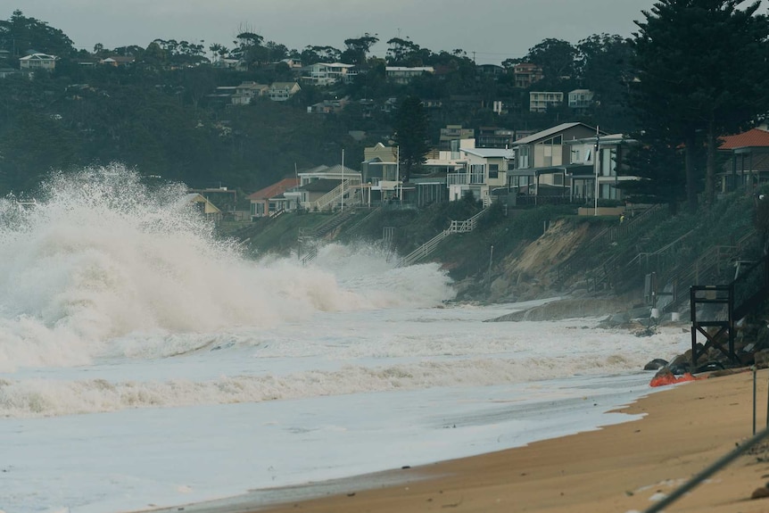 Waves break near homes causing cliffs to form from erosion