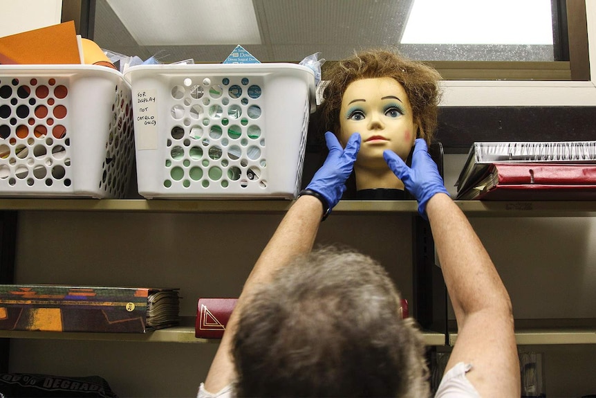 a woman's hands reaching for a mannequin's head