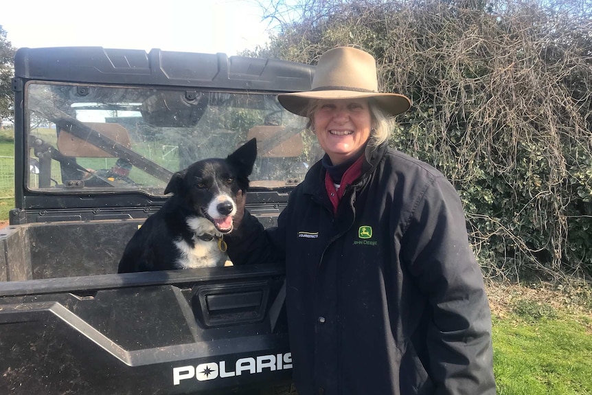 Cattle farmer Sally McCreath stands by a ute with her dog at their new property in Deloraine, Tasmania, in February 2019.