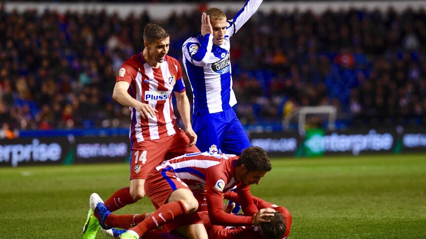 Fernando Torres lies on the ground as Atletico and Deportivo players call for help