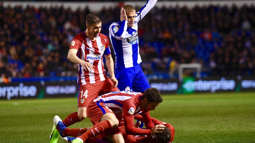 Fernando Torres lies on the ground as Atletico and Deportivo players call for help