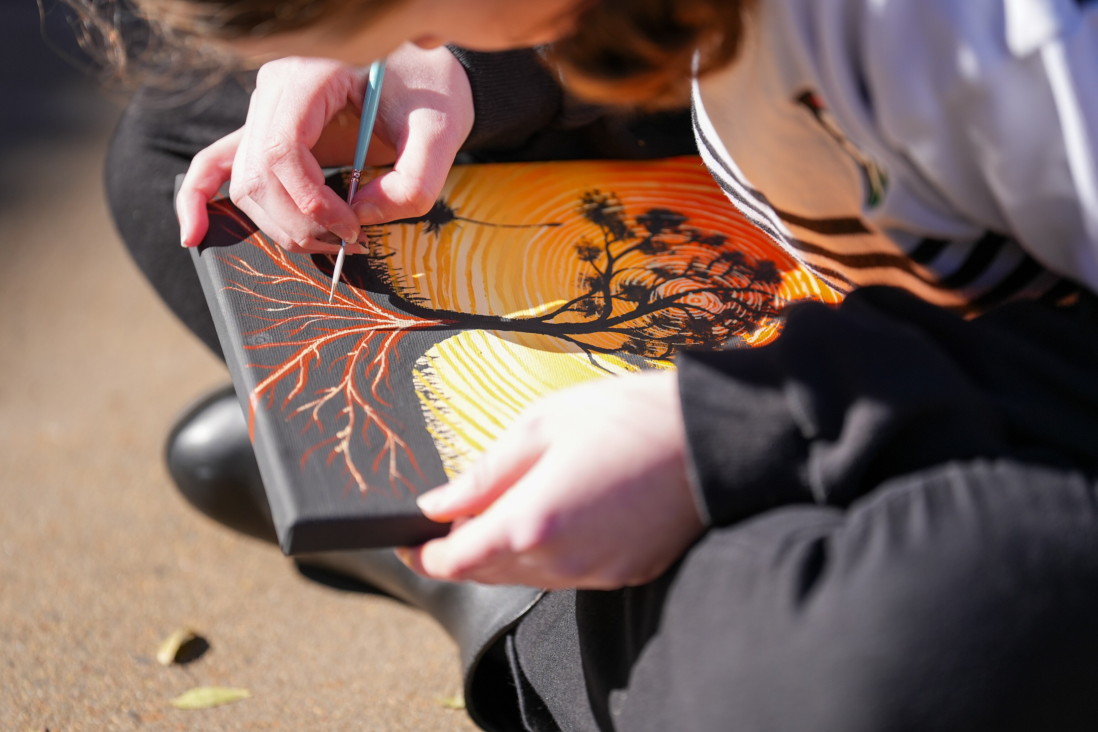 A student paints on a canvas.