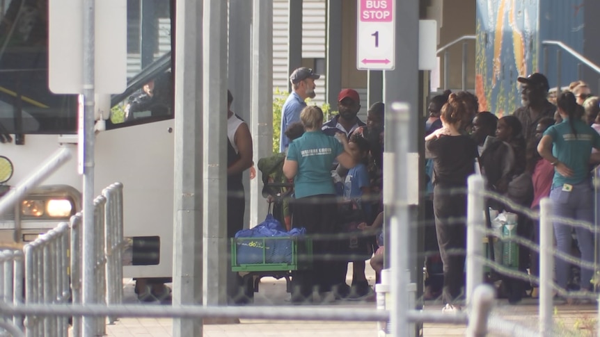 A group of people queuing up at a bus shelter, waiting to board.