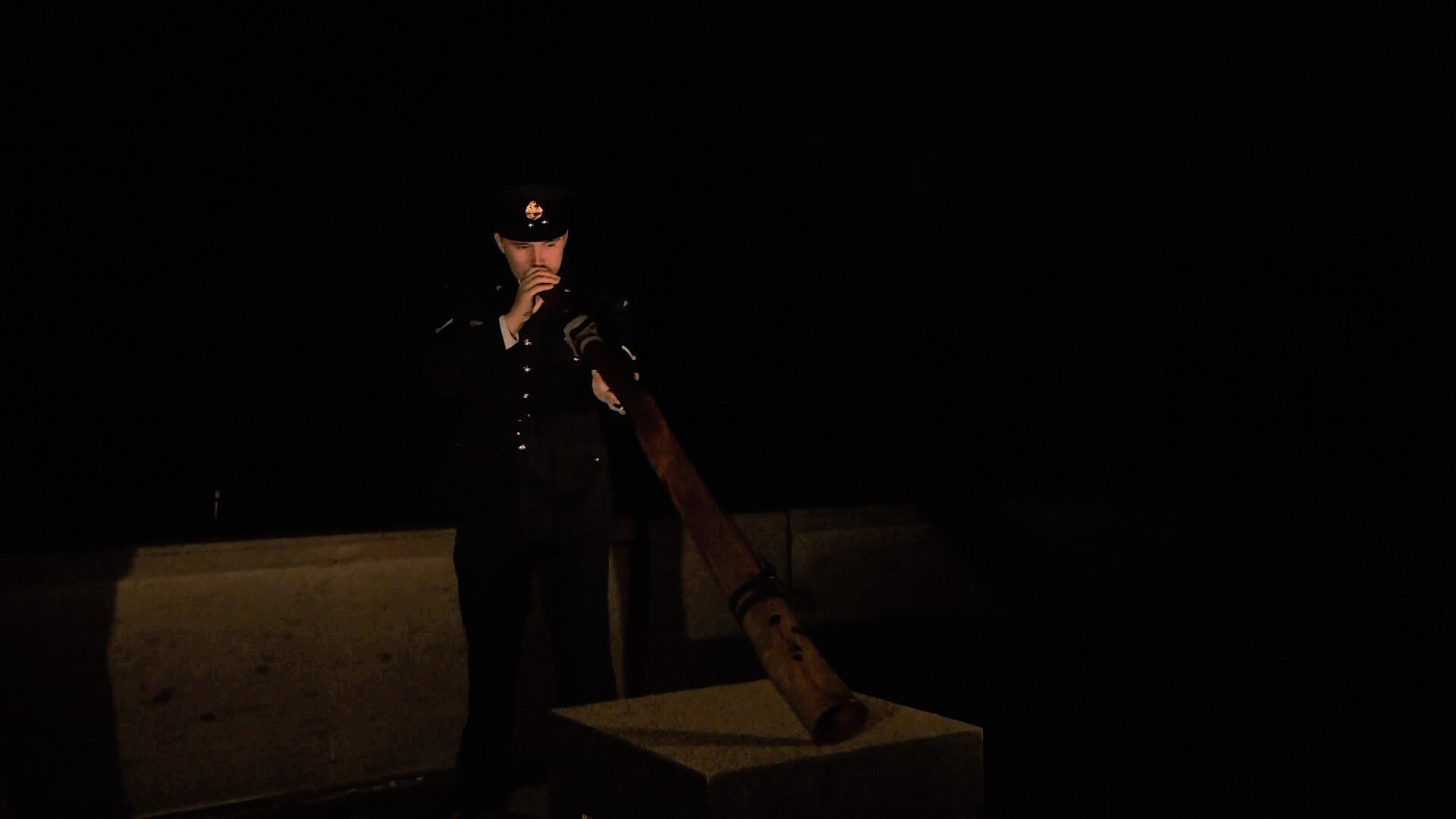 A man in uniform plays the didgeridoo