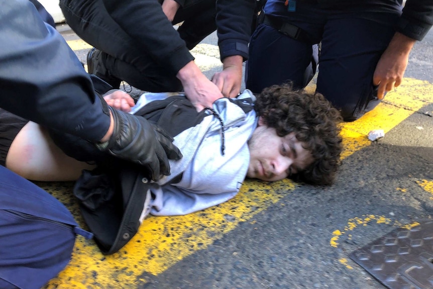 A man being held on the floor by police.