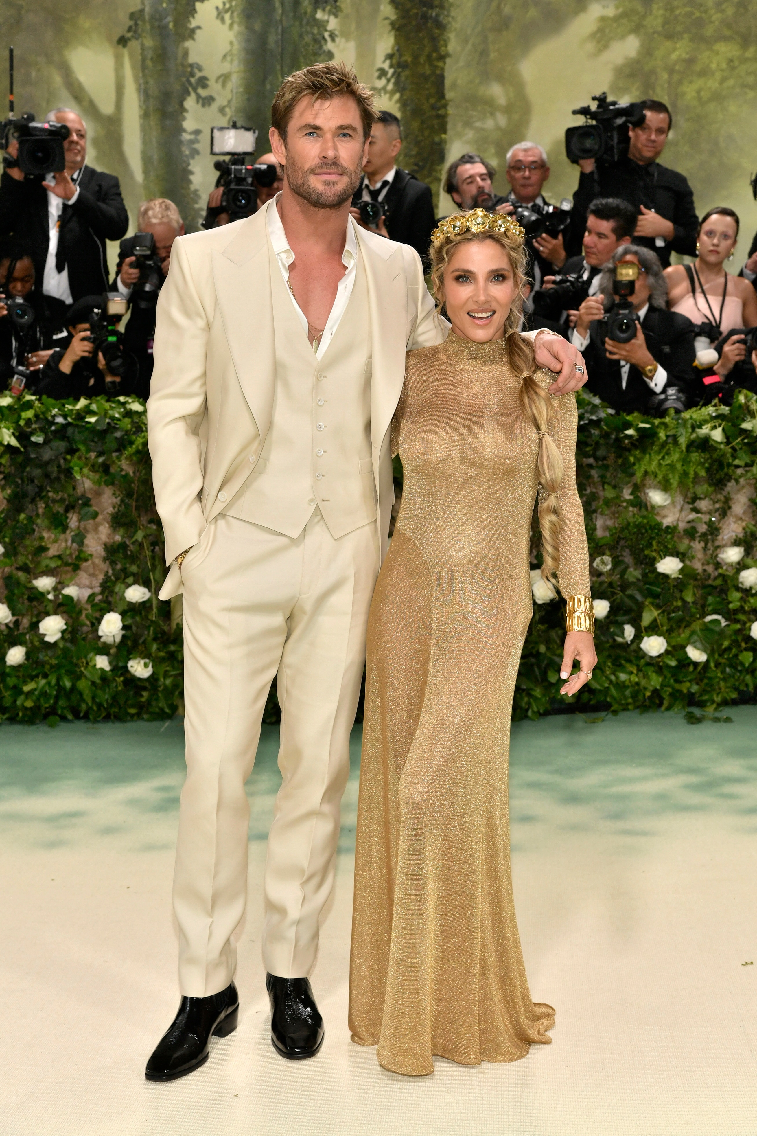 Chris Hemsworth wearing a silky champagne suit and Elsa Pataky in a long sleeve gold sparkly gown 