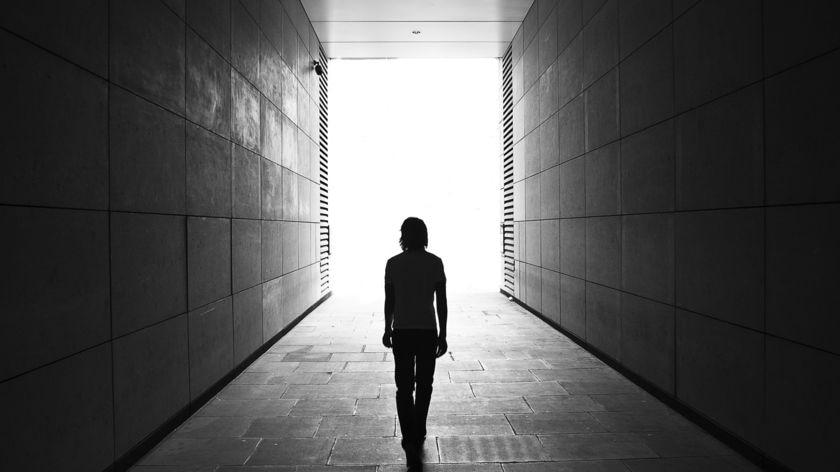 Young person walking through a tunnel.