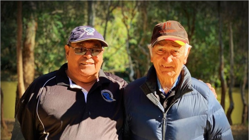 Uncle Rubin and Uncle Boydie stand with trees in the background, both are smiling.