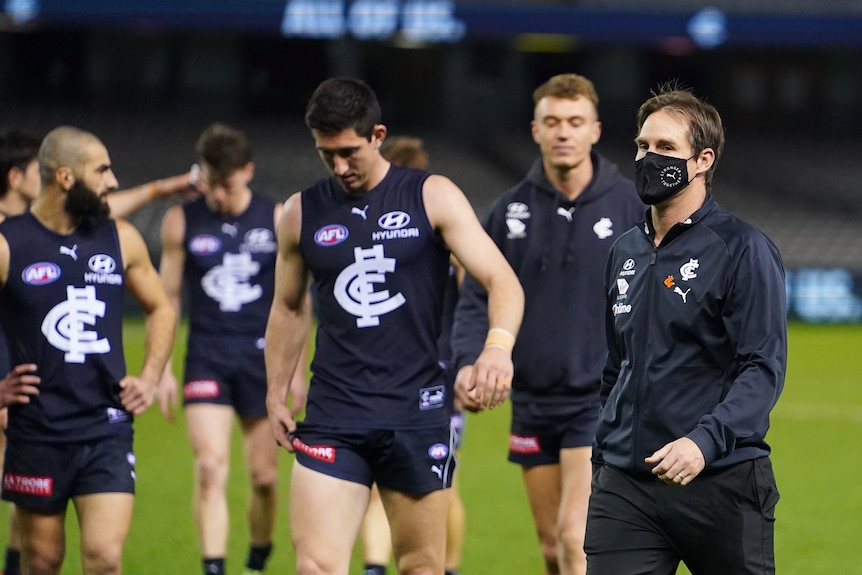 Carlton coach David Teague makes his way off the MCG after a loss beside his dejected players.ayers 