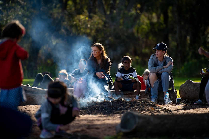 People sit at a campfire at a community event.