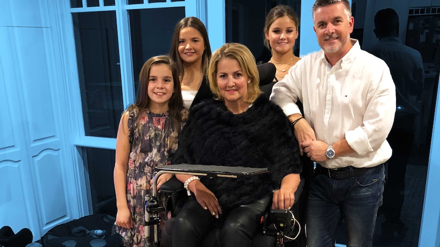 A woman in a wheelchair with three girls and a man standing behind her illustrating what its like parenting with a disability.