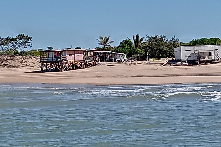 Two caravans on stilts at a beach.