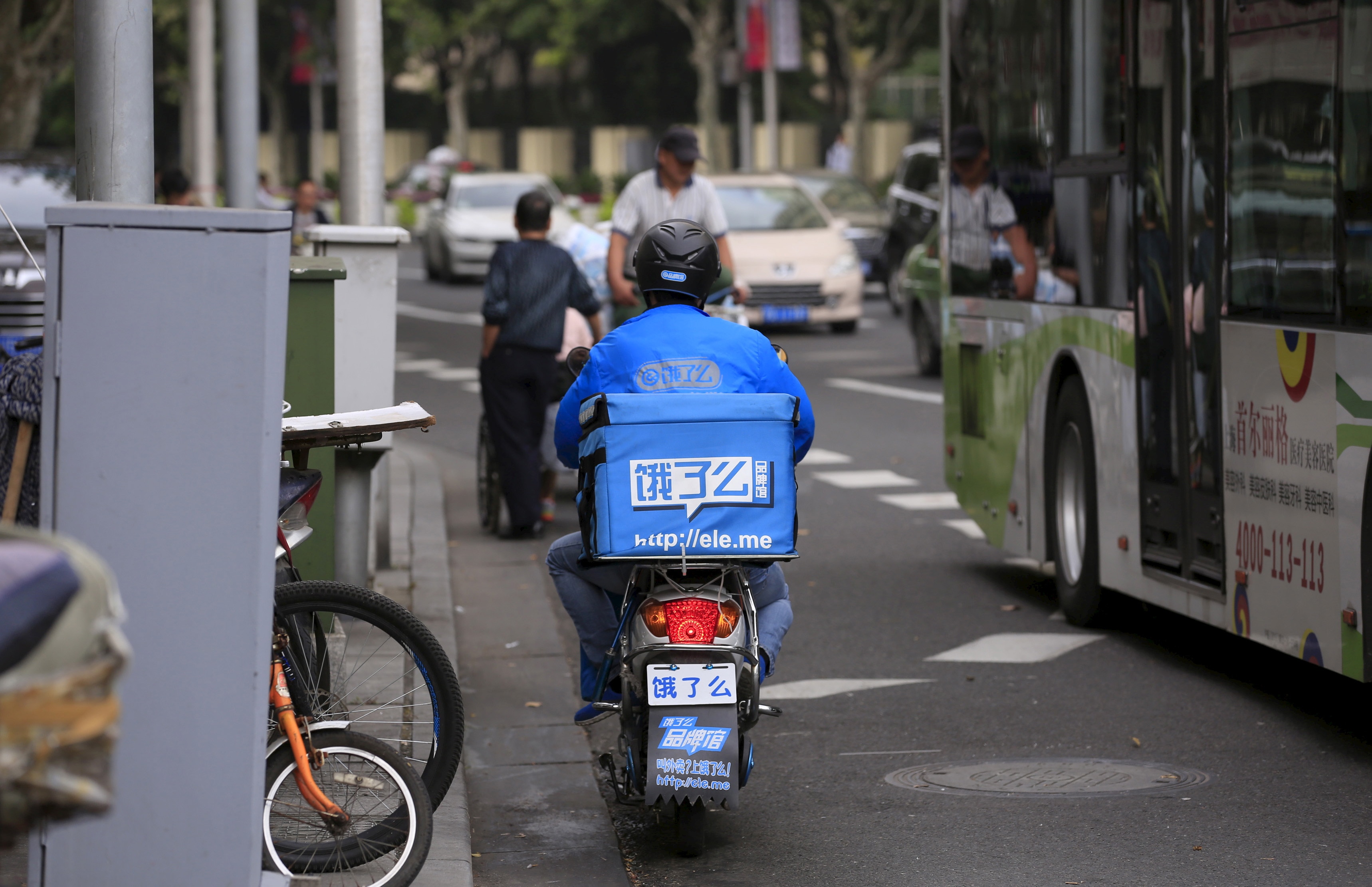 Um entregador de comida em uma motocicleta em uma rua chinesa