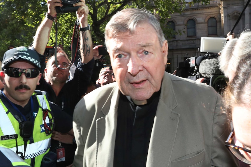 Cardinal George Pell walks into court, surrounded by police and media.