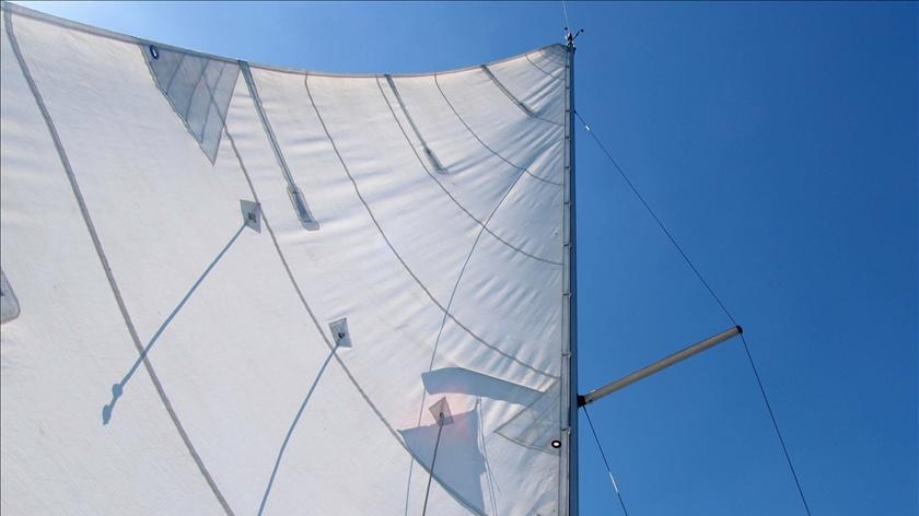 A yacht's sail billows in the wind