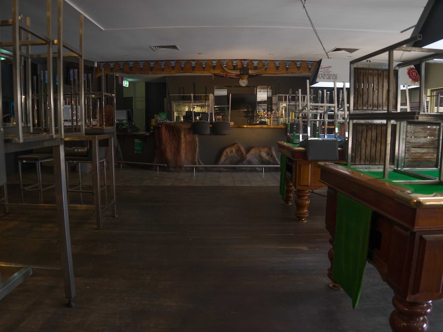 Stools upside down on top of bar benches and the pool table, in front of a wooden bar and bull horns