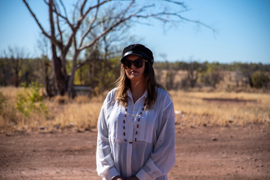 A young girl in a hat stands in the out back of the northern territory