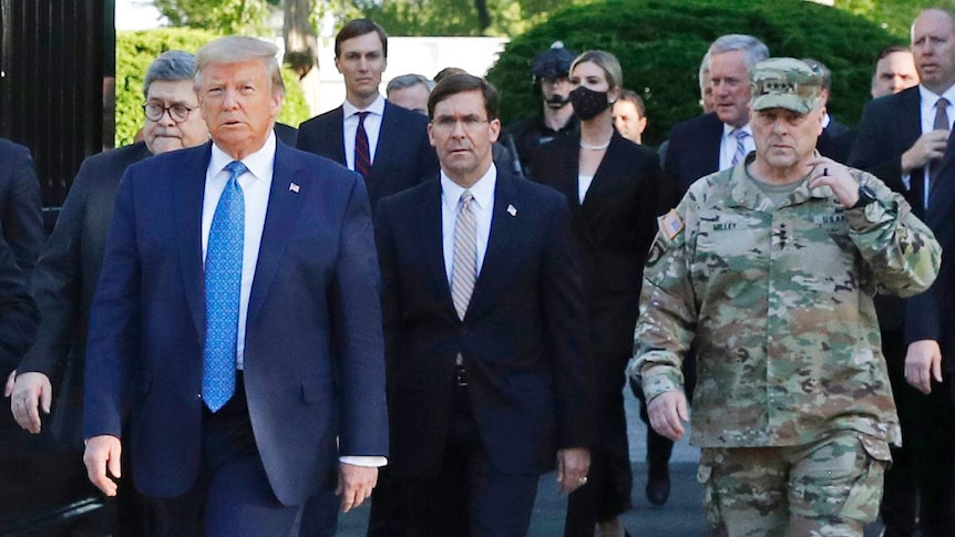 Mark Milley can be seen on the far right in camouflage fatigues walking as part of Mr Trump's entourage towards the church.