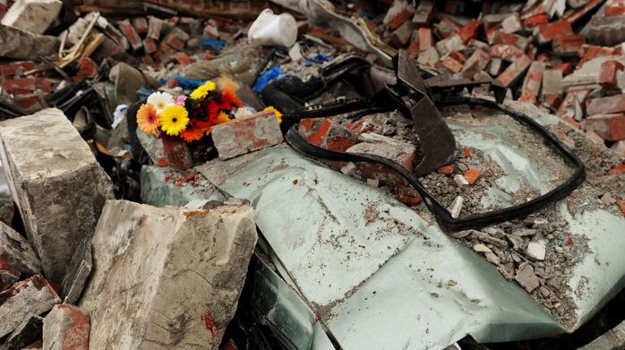 Flowers left in a crushed car pay tribute to a quake victim near Christchurch.