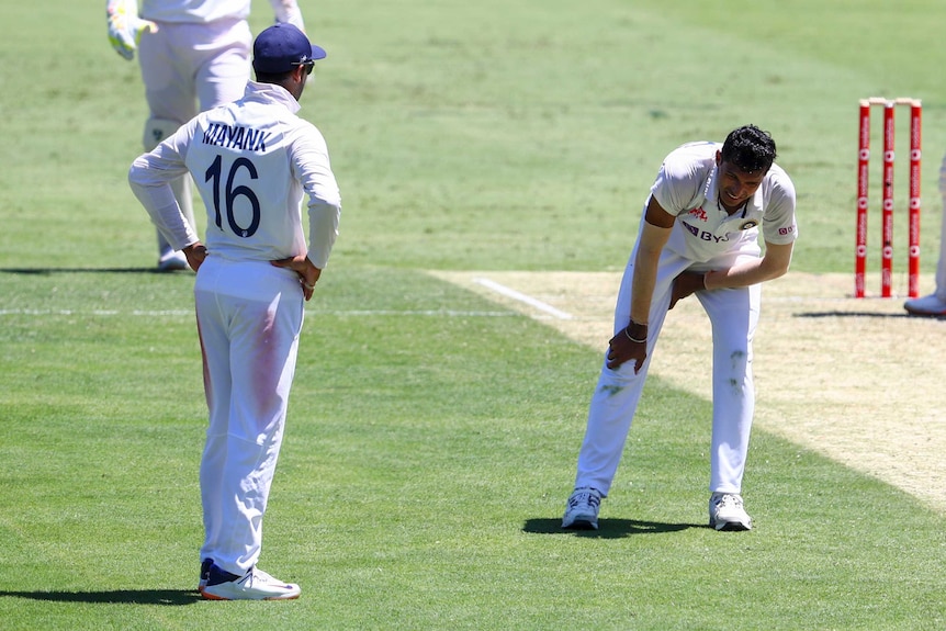 Navdeep Saini grabs his groin region as his face show pain. Mayank looks on.