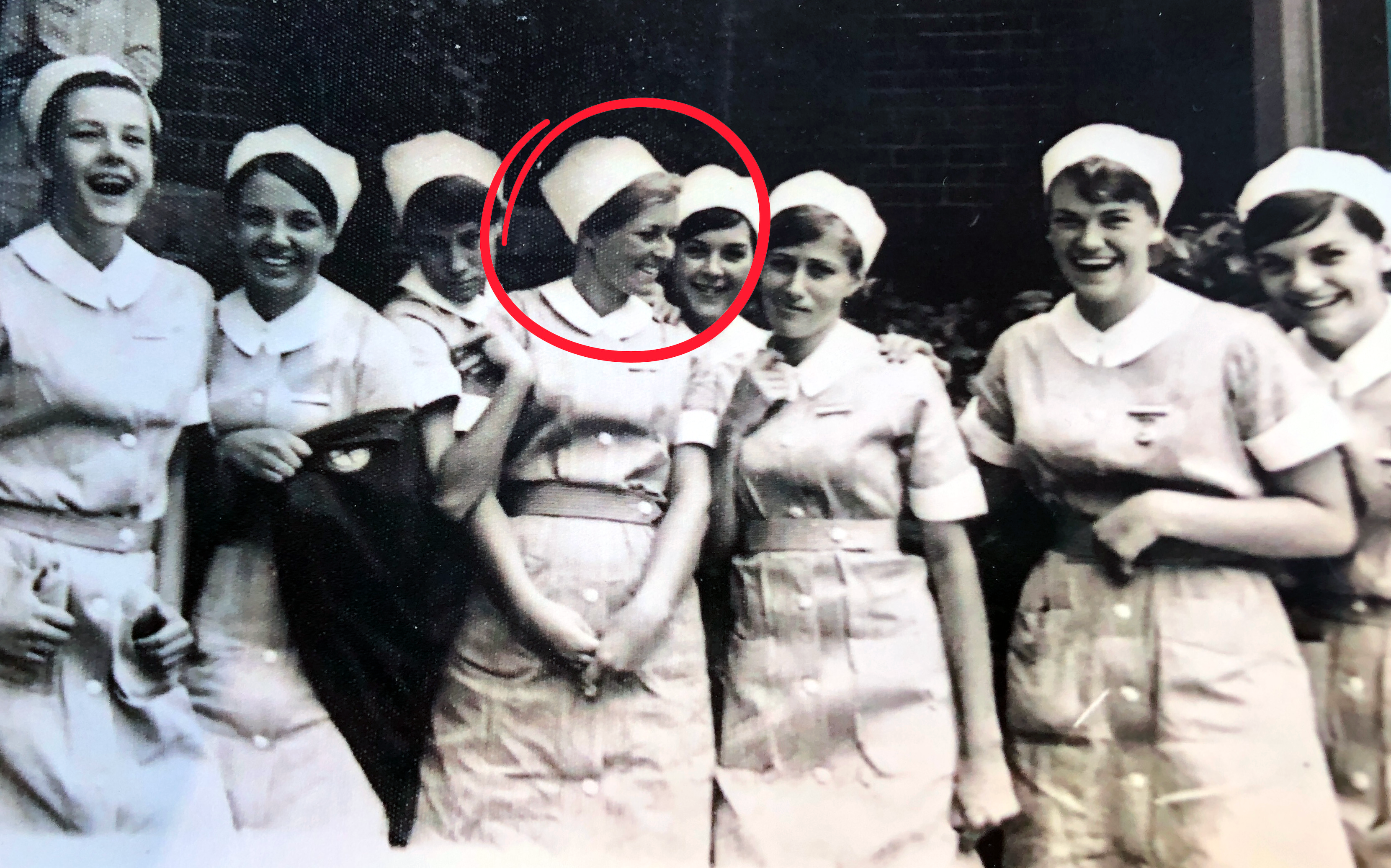 Black and white photograph of eight female nurses in uniform, laughing and smiling