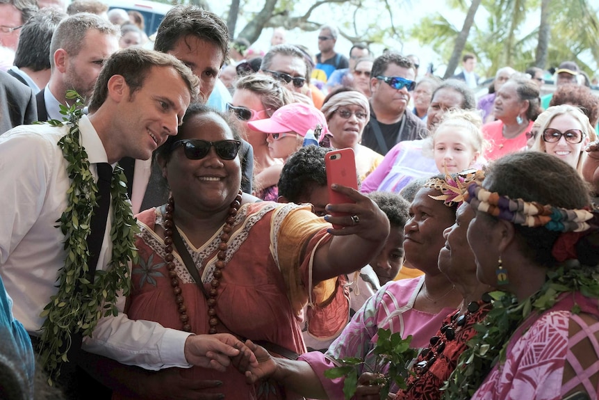 French President Emmanuel Macron poses for a selfie with a woman in New Caledonia.