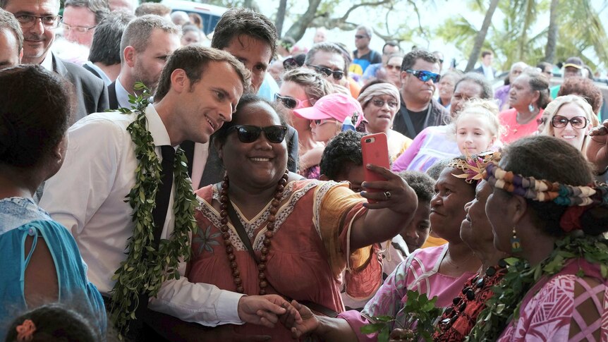 French President Emmanuel Macron poses for a selfie with a woman in New Caledonia.